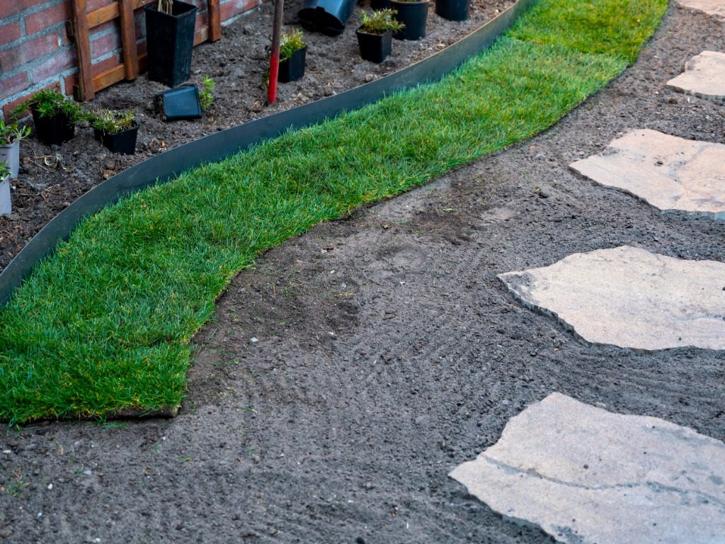 Making of natural green lawn in garden with rolls of green grass, garden renovation works in spring